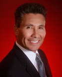 Smiling man in a suit against red background.