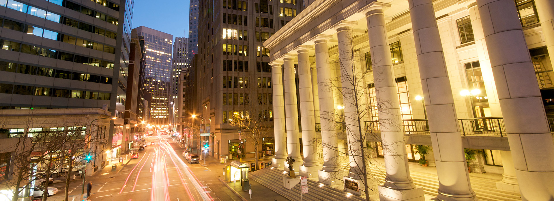 City street at dusk with illuminated buildings.