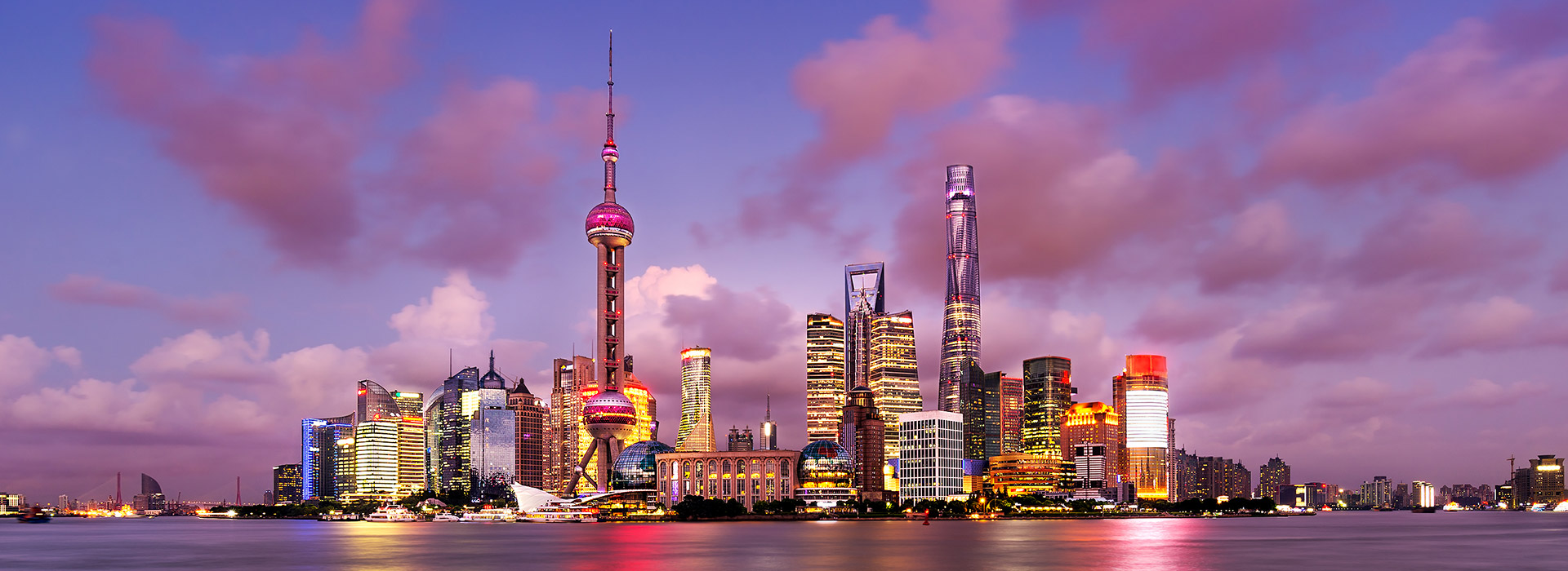 Shanghai skyline at dusk with colorful lights.