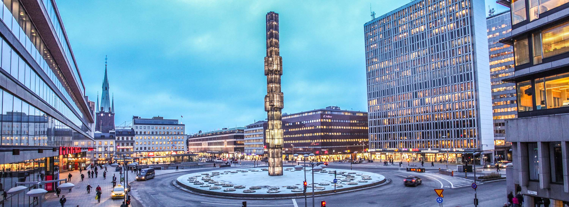 City square with modern buildings and monument.